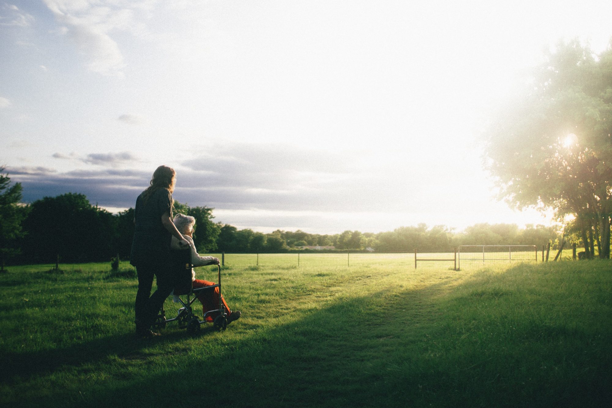 A carer walking outdoors with a client at sunset